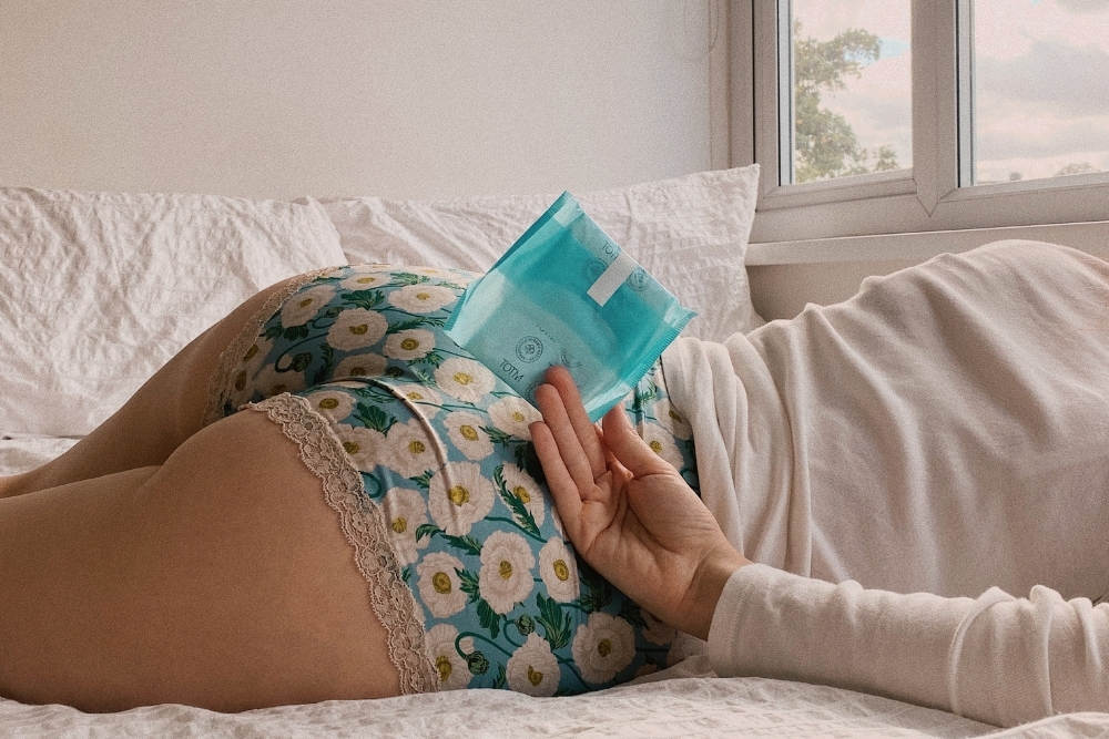 Hold sanitary pad whilst lying down on bed