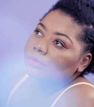 Head shot of a Black female in a yellow strappy top. She is looking up to the top left of the camera. Headache during periods