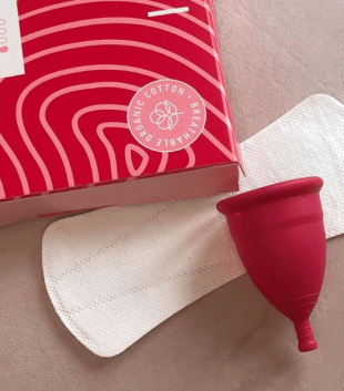 TOTM's reusable zero-waste menstrual cup, organic cotton liner and organic cotton light flow pads box on pink background