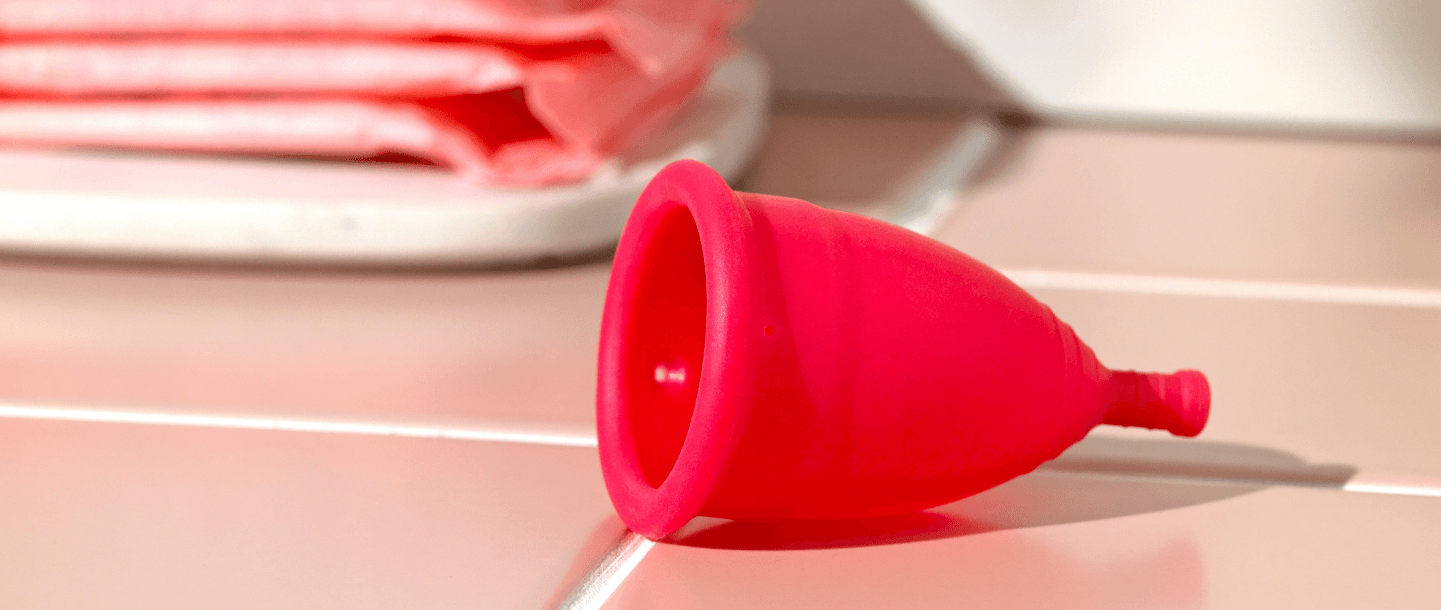 TOTM's zero waste reusable menstrual cup laying on it's side on pink tiles