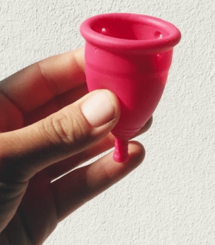 Close-up of a hand holding a TOTM reusable zero-waste menstrual cup against a white background