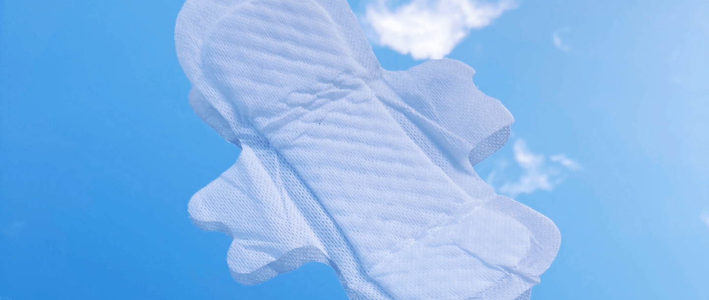 TOTM's light flow organic cotton pad out of wrapper on a blue background with cloud